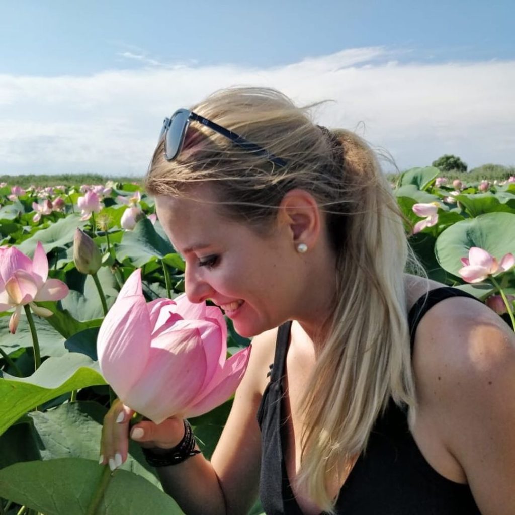 Excursii Delta Dunarii- O femeie miroase o floare de lotus roz.